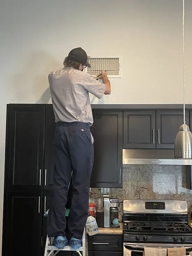 Technician inspecting an air vent during HVAC service in Benner